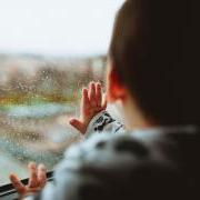 Baby touching rain spotted window